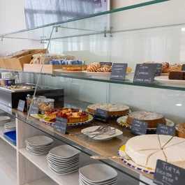 Vetrina con dolci assortiti e piatti impilati in un locale luminoso