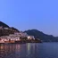 Costa illuminata di un villaggio sul mare al crepuscolo con montagne sullo sfondo
