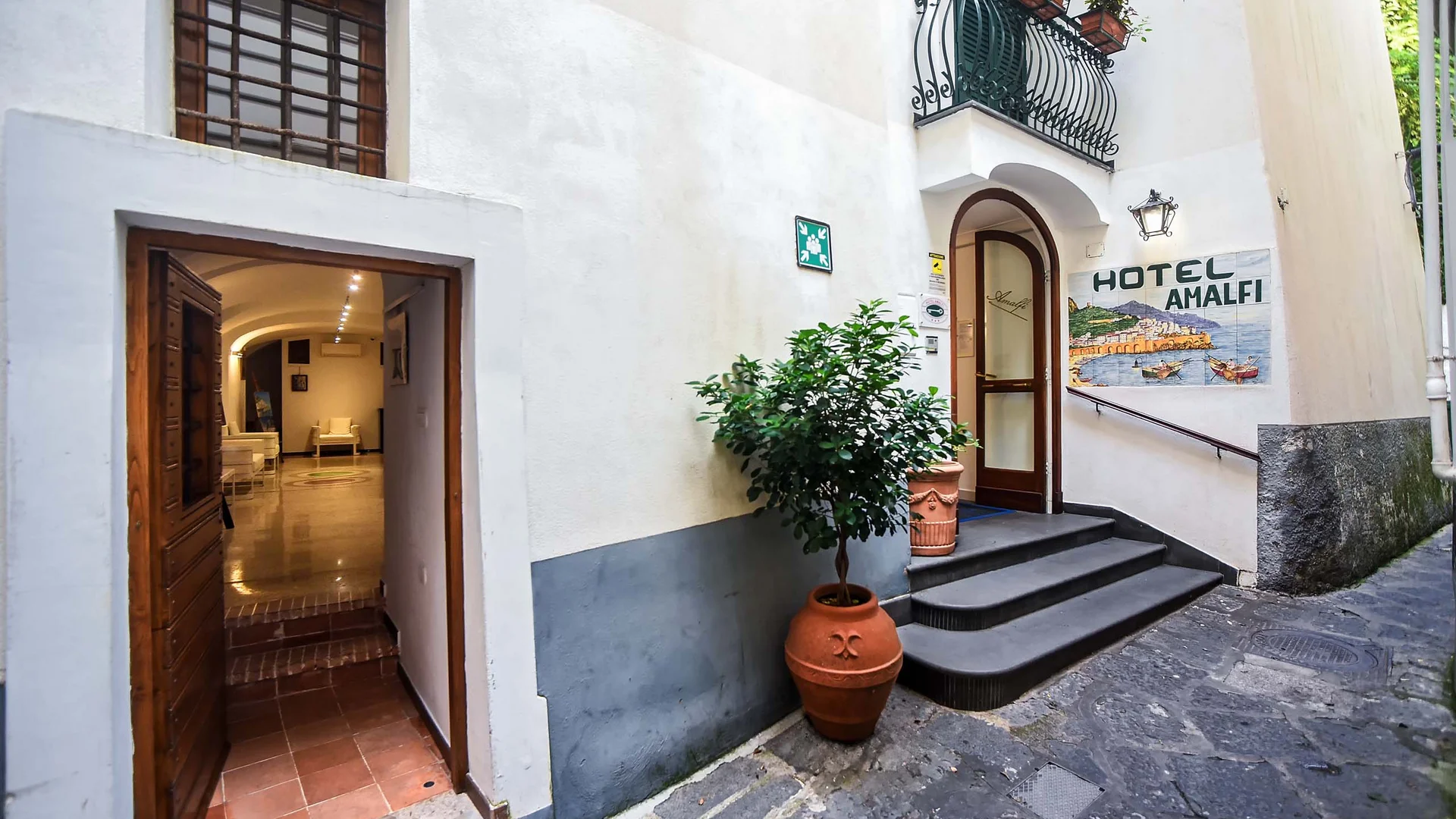 Ingresso di Hotel Amalfi in una strada lastricata con piante in vaso