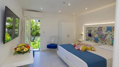 Camera d'albergo luminosa con letto matrimoniale e porta aperta su balcone verde