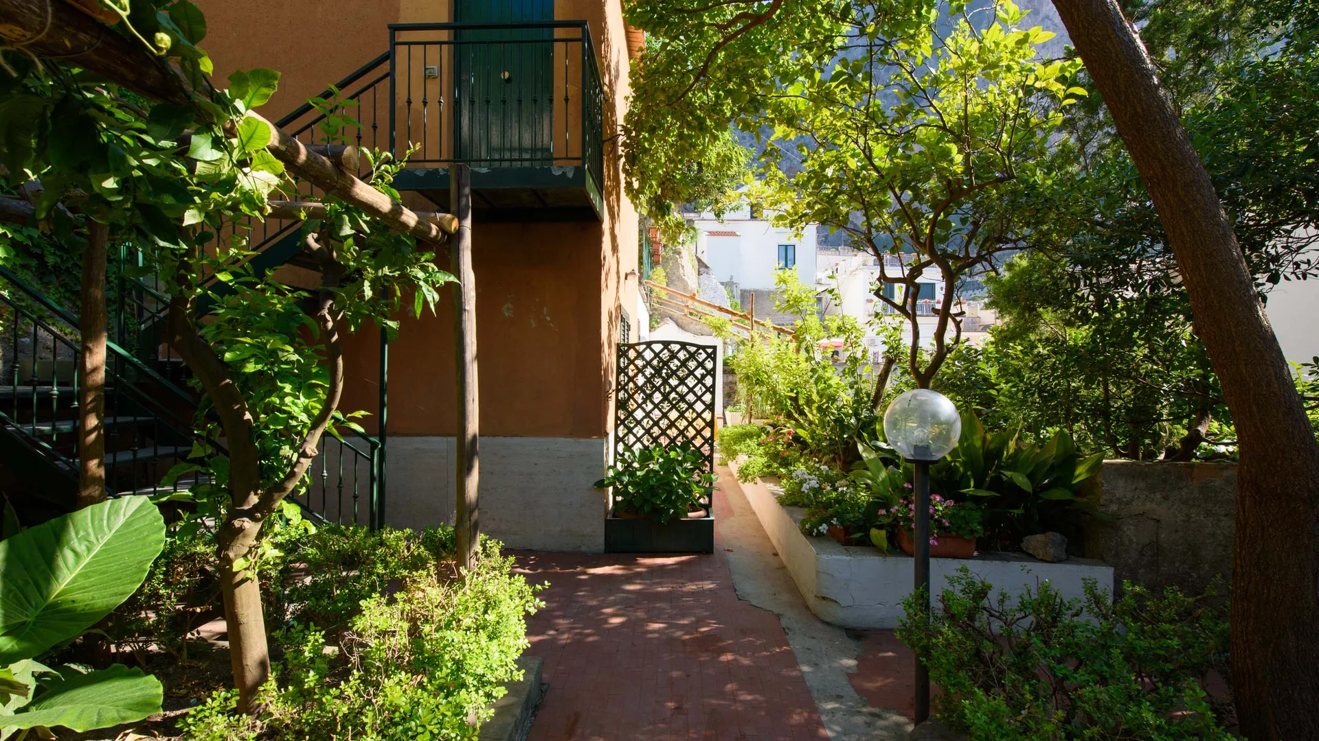 Ingresso di casa con giardino e piante rigogliose in zona soleggiata