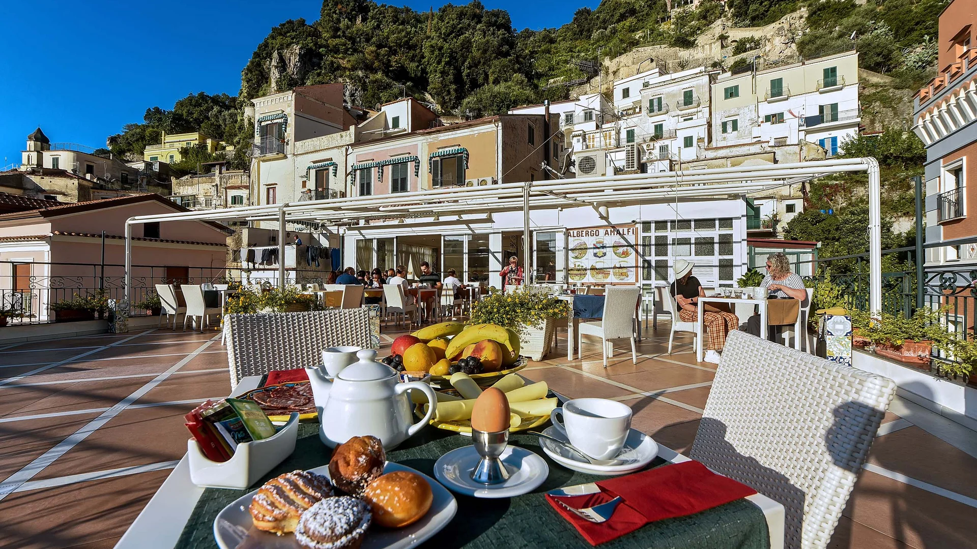 Colazione all'aperto con dolci e frutta su terrazza soleggiata ad Amalfi