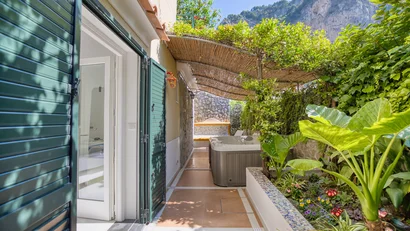Terrazza con vasca idromassaggio e piante verdi sotto pergolato di canne