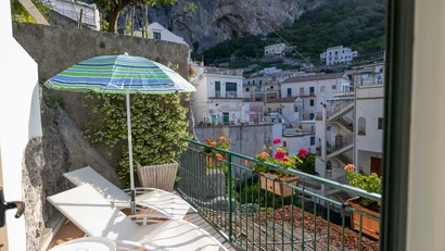 Terrazza con lettini, ombrellone e vista su case bianche e montagna