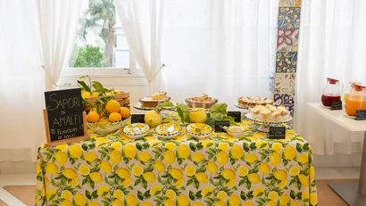 Tavolo con tovaglia a limoni e dolci tipici di Amalfi con frutta e succhi
